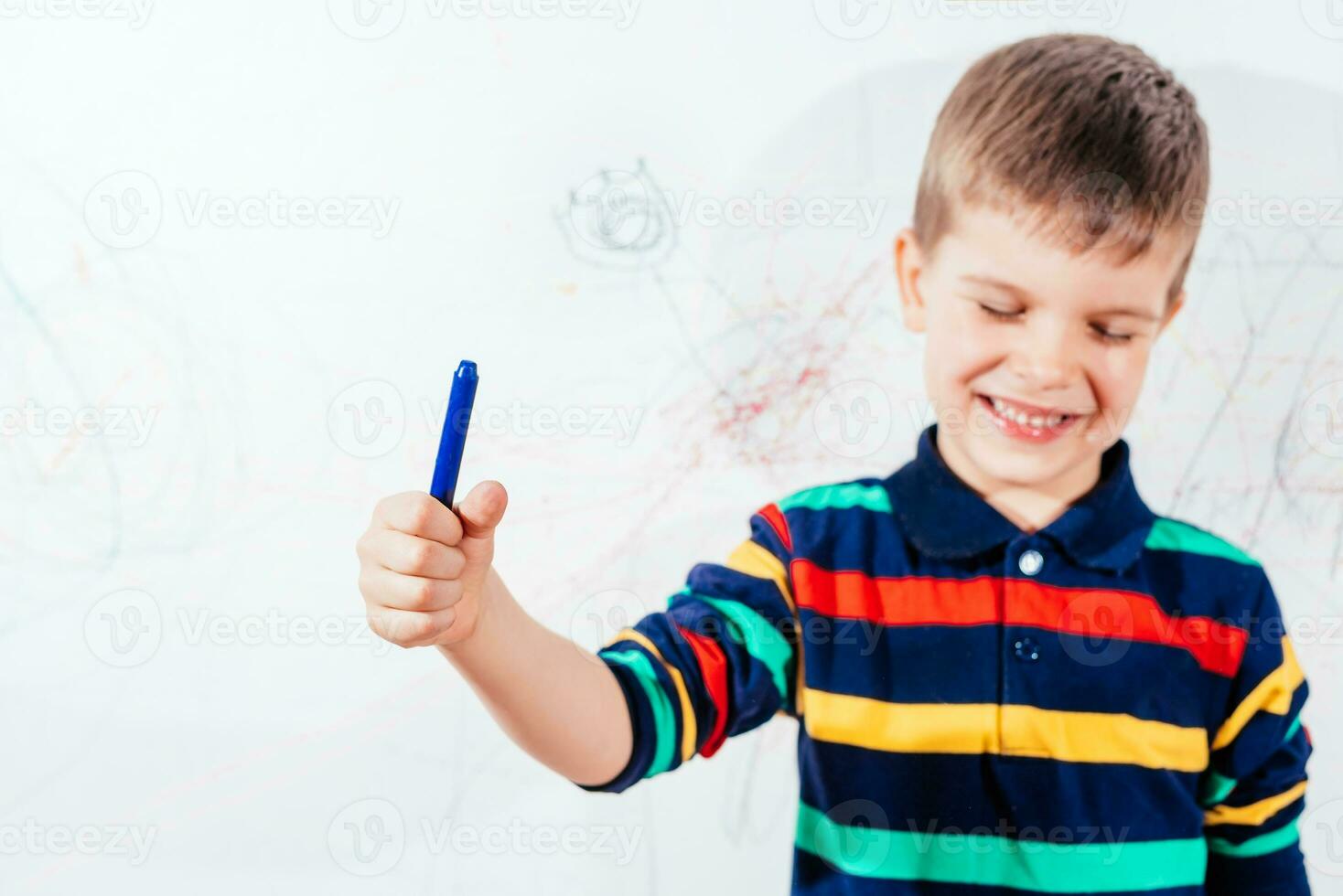 il bambino disegna su il parete con un' pastello. il ragazzo è impegnato nel creatività a casa foto