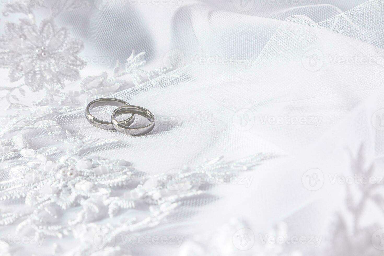 Due classico nozze anelli nel bianca oro contro un' bianca bordatore e perla bridal velo. un' copia di il spazio. selettivo messa a fuoco. foto
