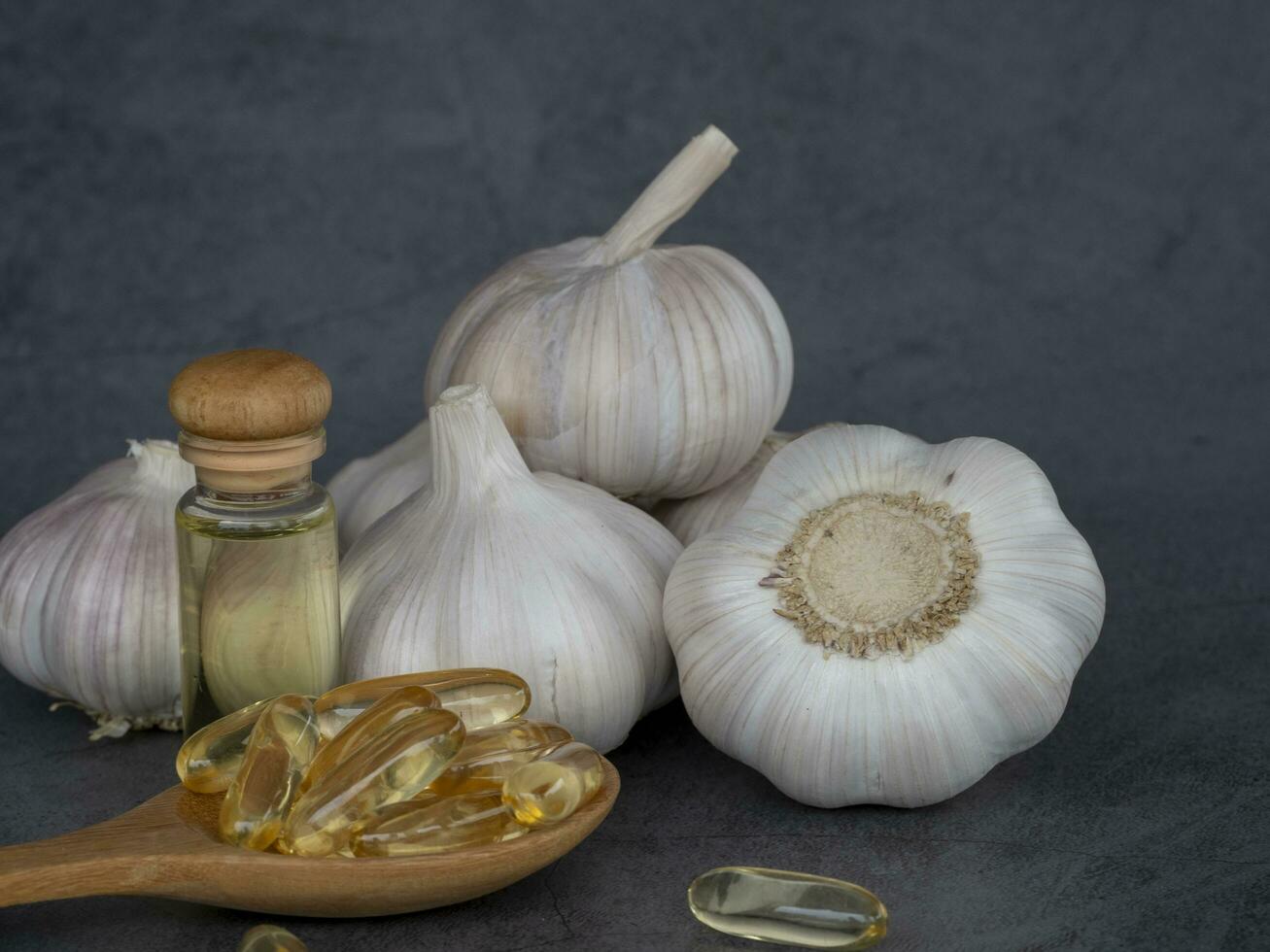 capsula aglio olio nel di legno cucchiaio con freddo stampa aglio olio, il beneficiare di aglio capsule ridurre sangue pressione, ridurre sangue Grasso, colesterolo, impedire cancro. foto