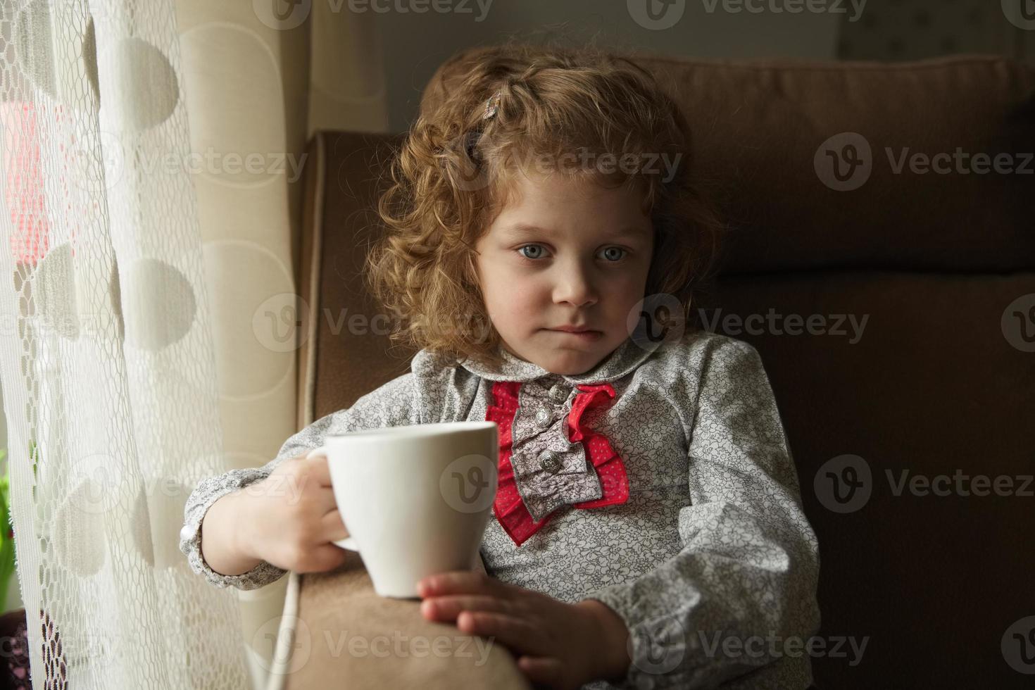 bambina premurosa con una tazza foto