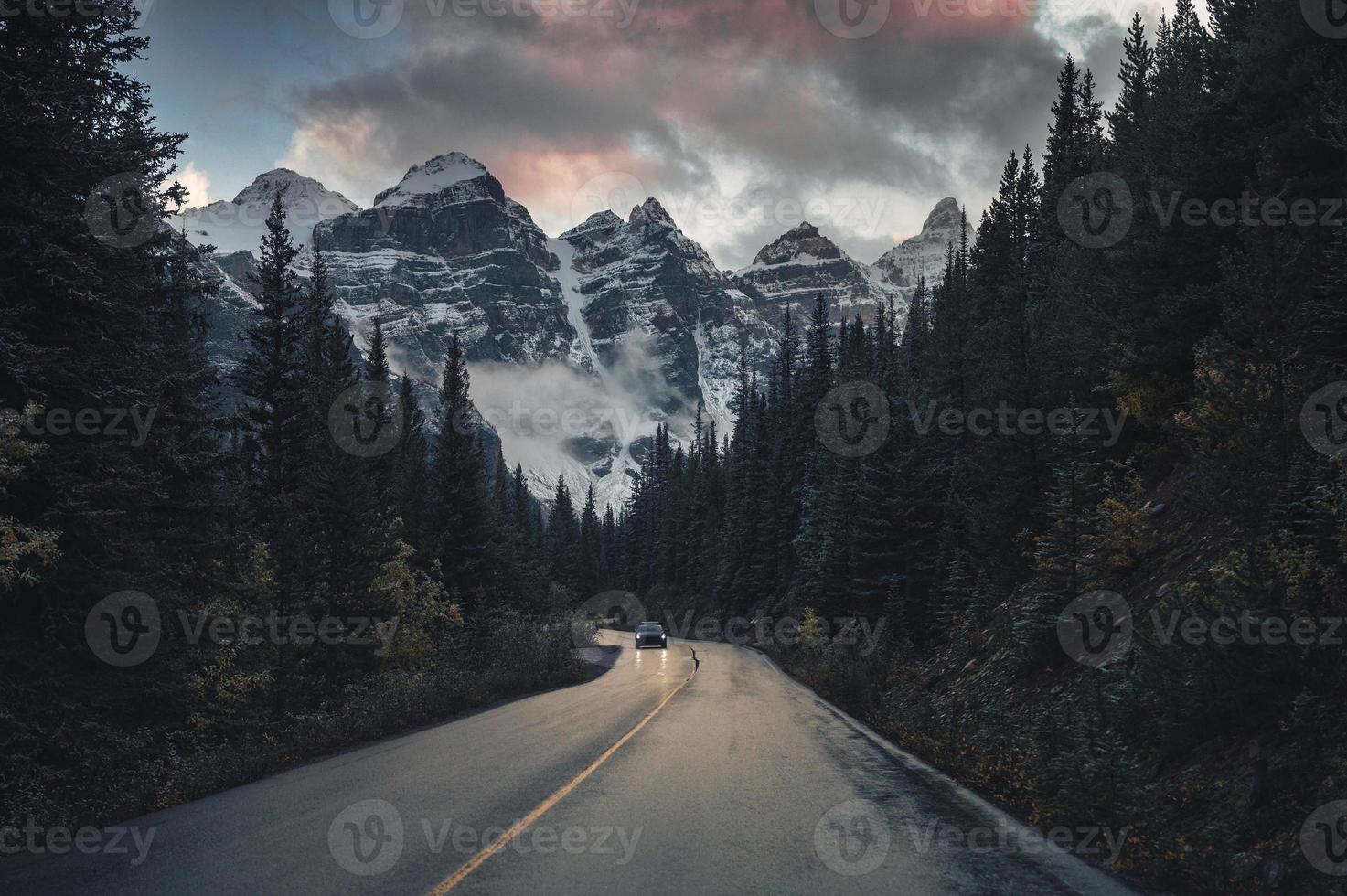 viaggio su strada con montagne rocciose nella foresta di pini vicino al lago morenico nel parco nazionale di Banff foto