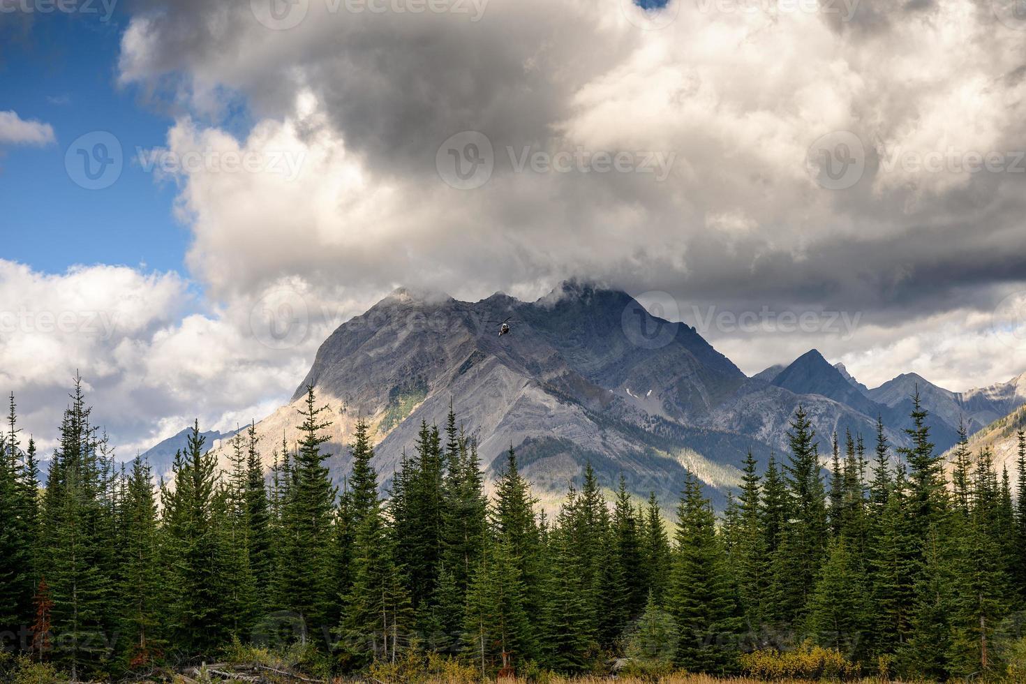 elicottero commerciale che vola con montagne rocciose nel parco provinciale di assiniboine foto