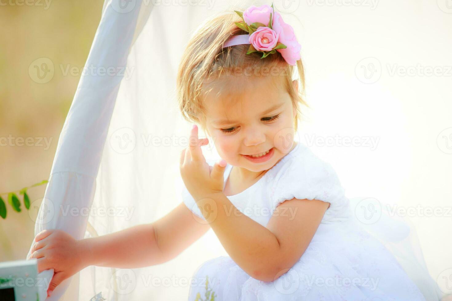poco ragazza regola sua capelli di capanna per Giochi. bambino con bellissimo acconciatura nel bianca vestire. foto