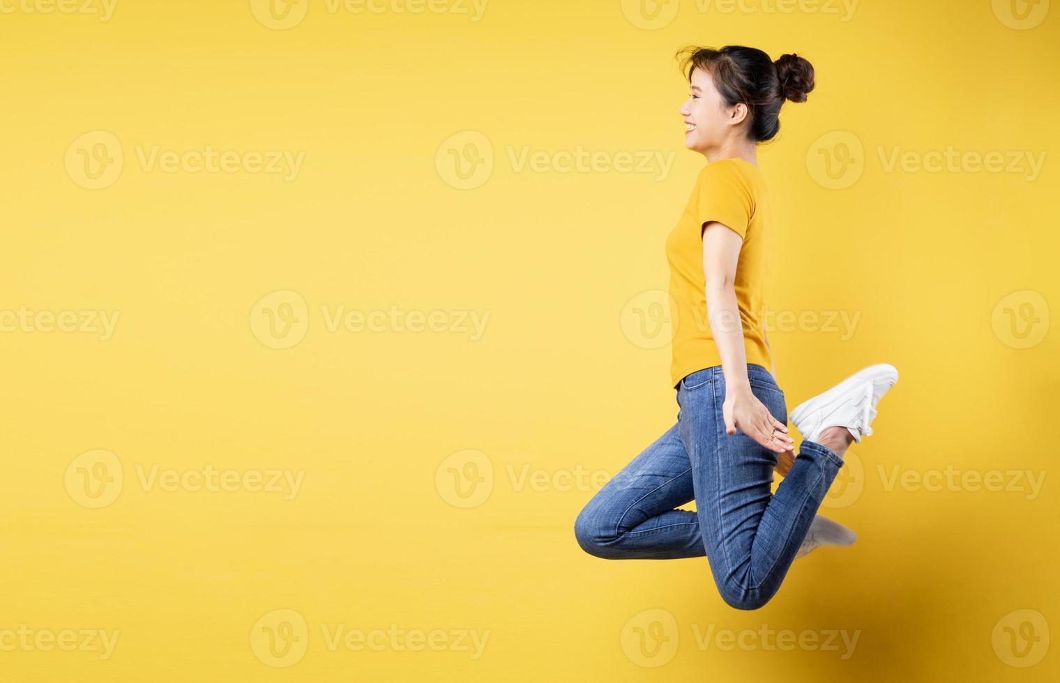 ritratto fotografico per tutta la lunghezza di una ragazza allegra che salta in piedi per celebrare la vittoria isolata su uno sfondo colorato di blu pastello foto