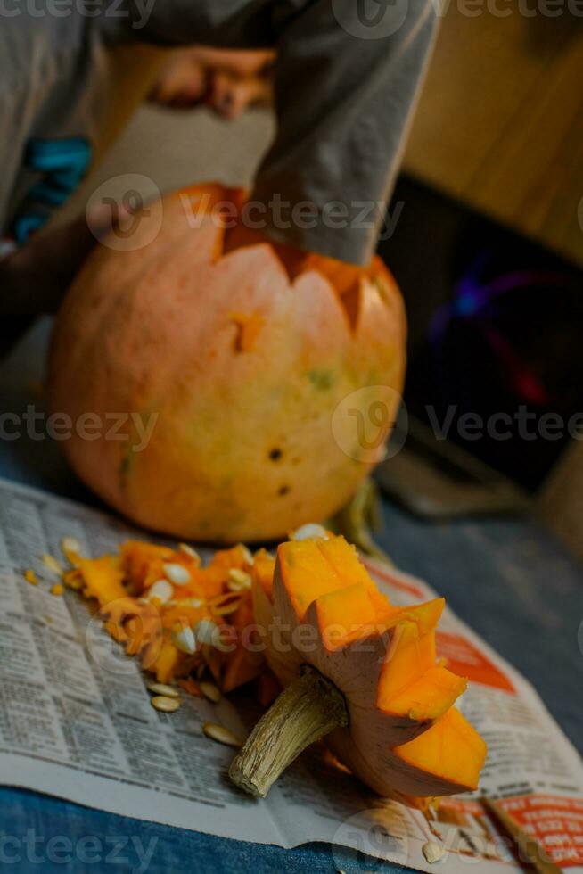 bambino scolpisce a partire dal un' zucca. famiglia divertimento attività. arved zucche in jack-o-lantern per Halloween. foto