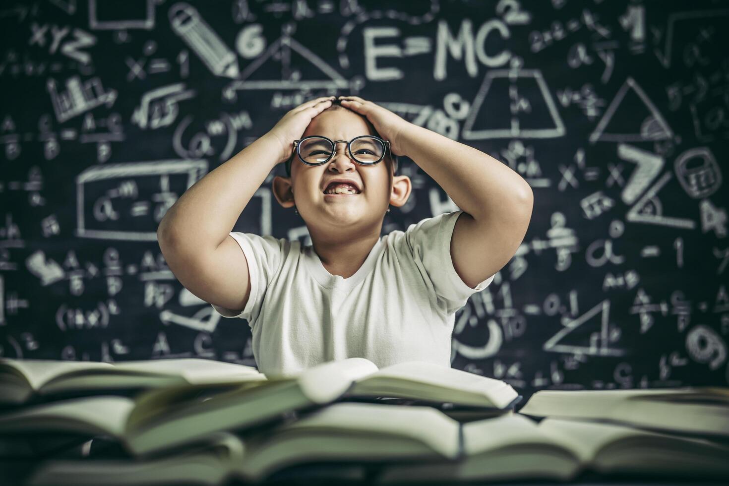 i ragazzi con gli occhiali scrivono libri e pensano in classe foto