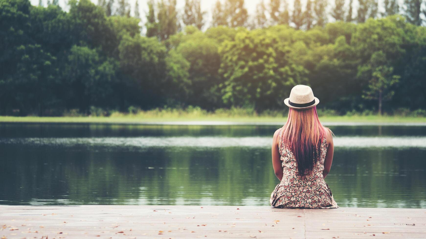 giovane donna seduta sul molo e guardando il fiume. foto