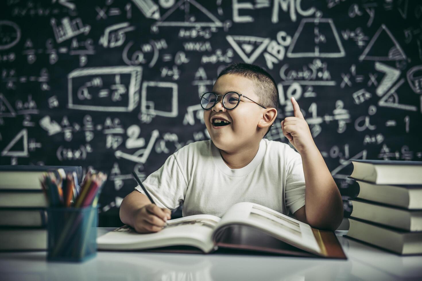 i ragazzi con gli occhiali scrivono libri e pensano in classe foto