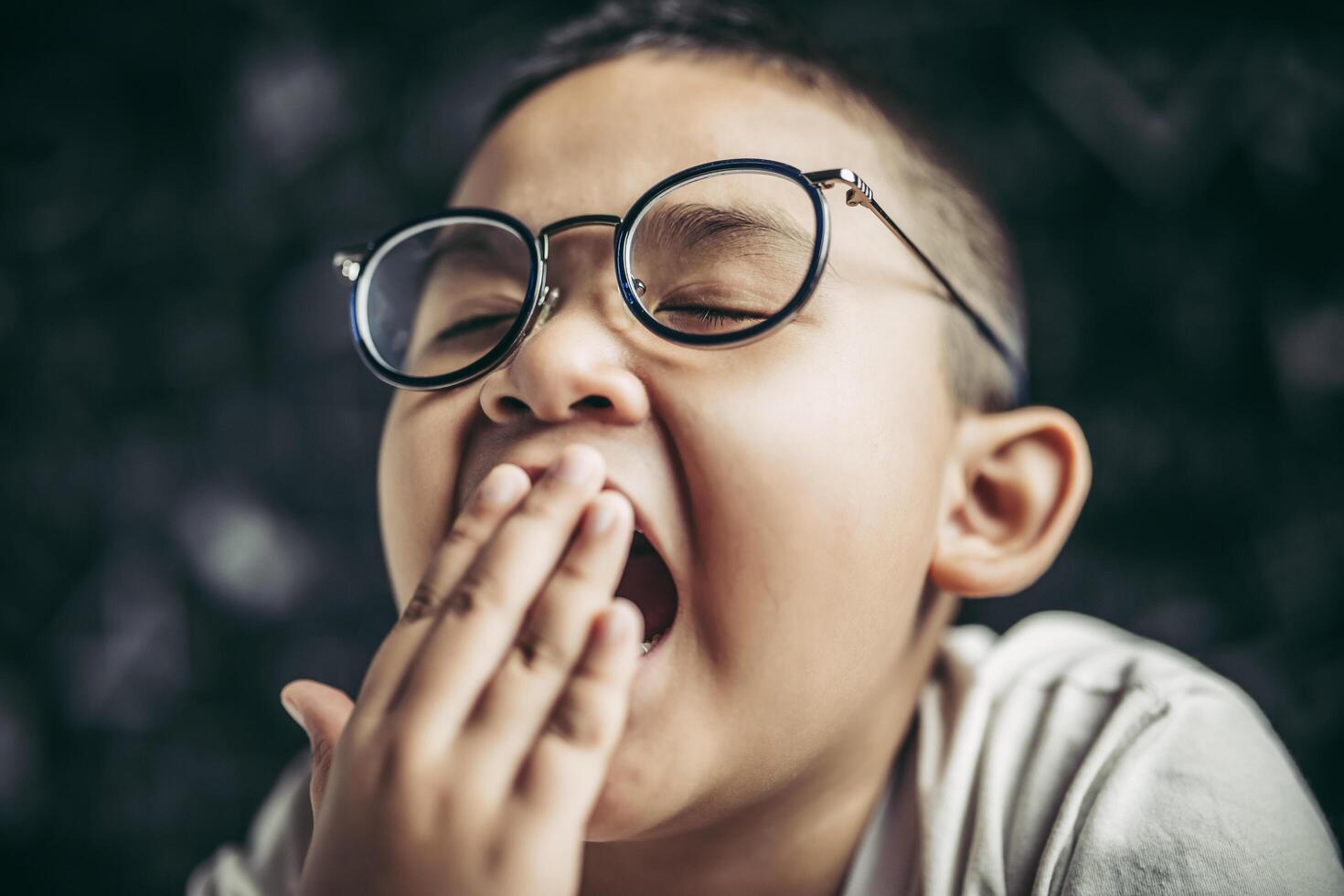 un ragazzo con gli occhiali che studia e assonnato. foto