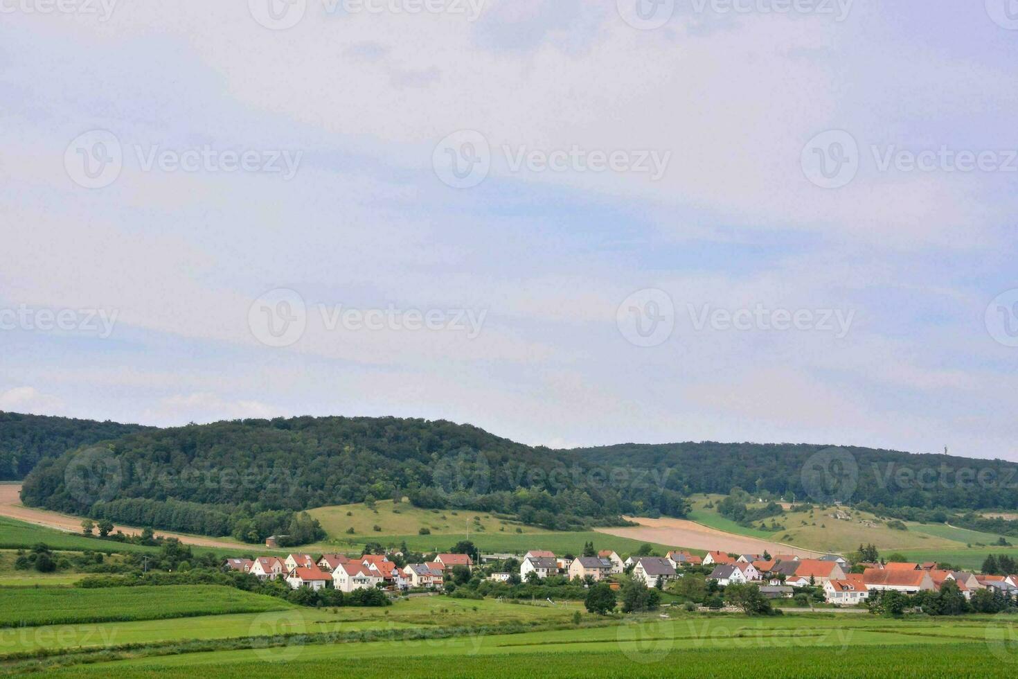 un' piccolo villaggio nel il campagna con un' collina nel il sfondo foto