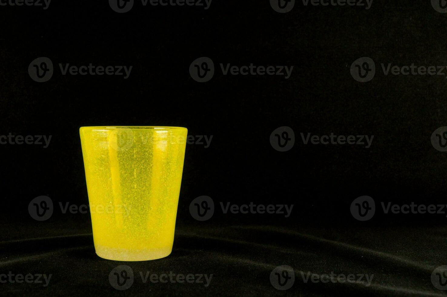 un' giallo tiro bicchiere seduta su un' nero superficie foto