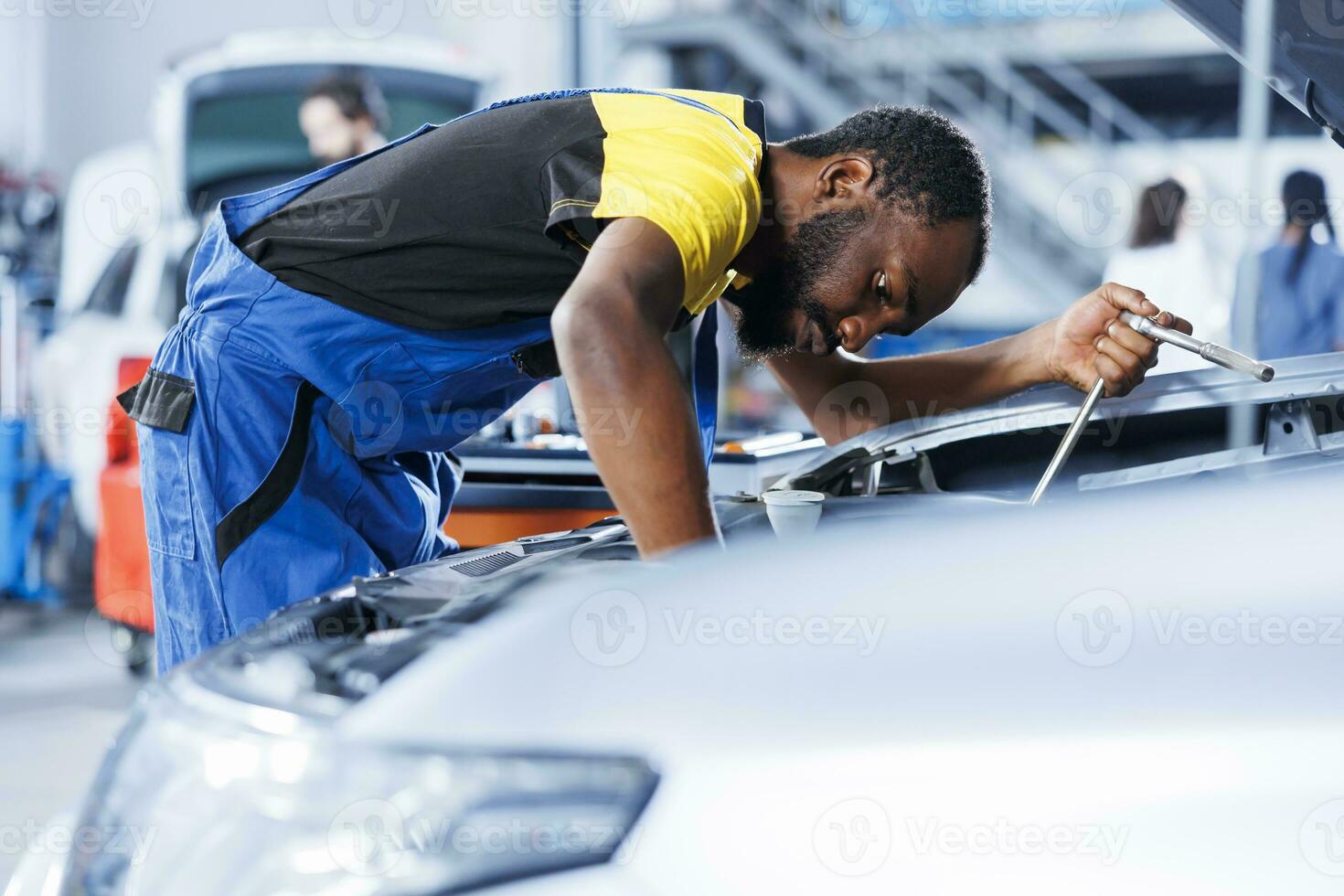 bipoc specialista nel auto servizio utilizzando professionale meccanico attrezzo per riparazione rotto accensione sistema. concesso in licenza specialista nel box auto fissaggio cliente automobile, garantendo ottimale settore automobilistico prestazione foto