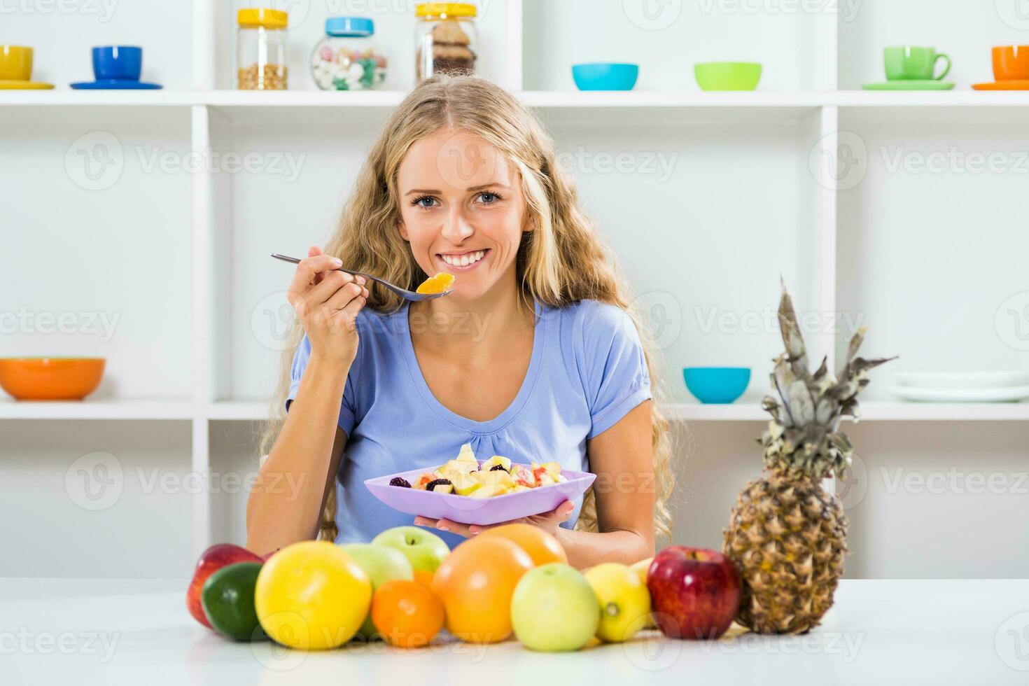 bellissimo ragazza gode mangiare frutta insalata a sua casa foto