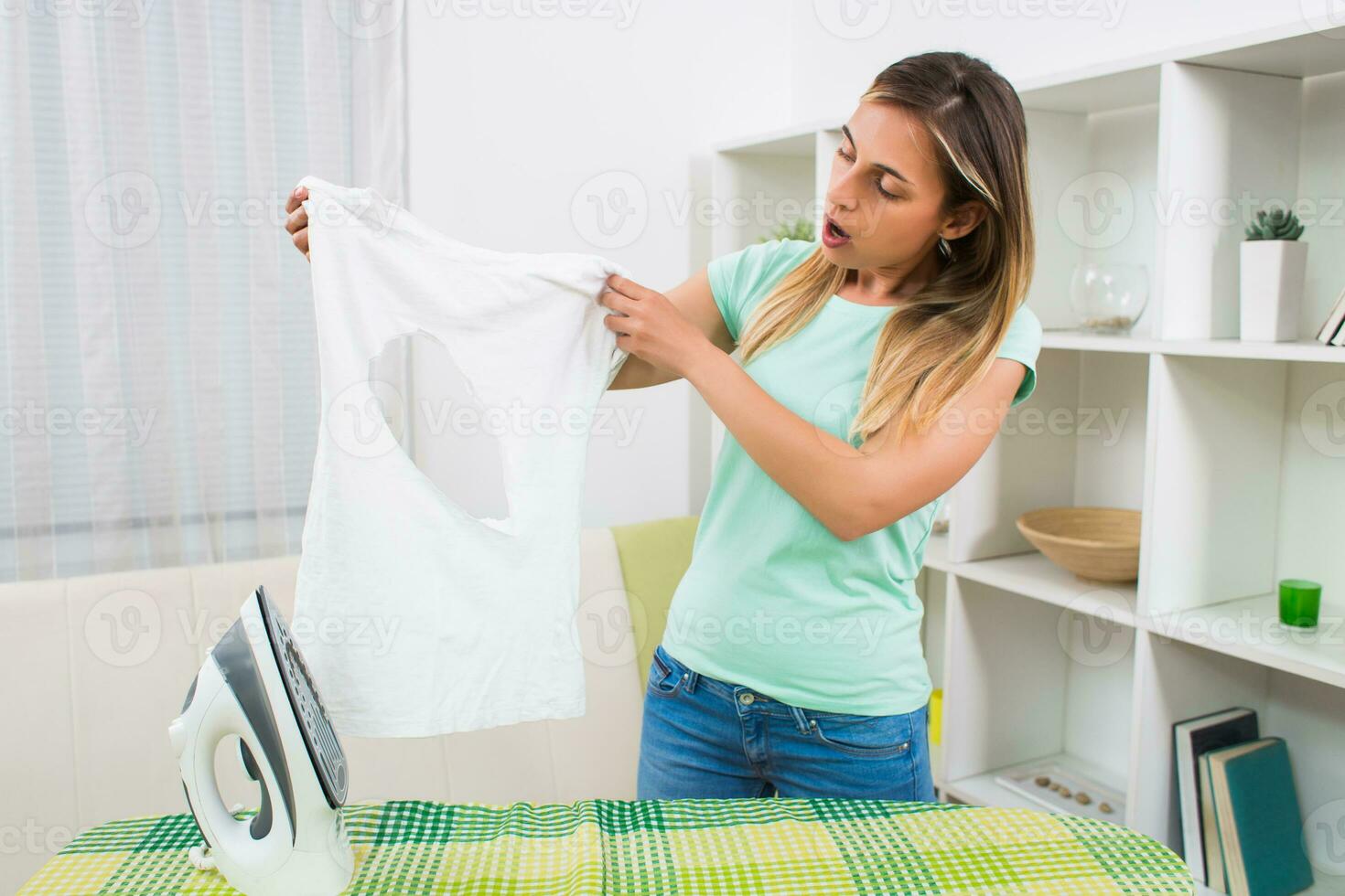 disperato donna fatto un' buco su sua maglietta e danneggiato sua ferro foto