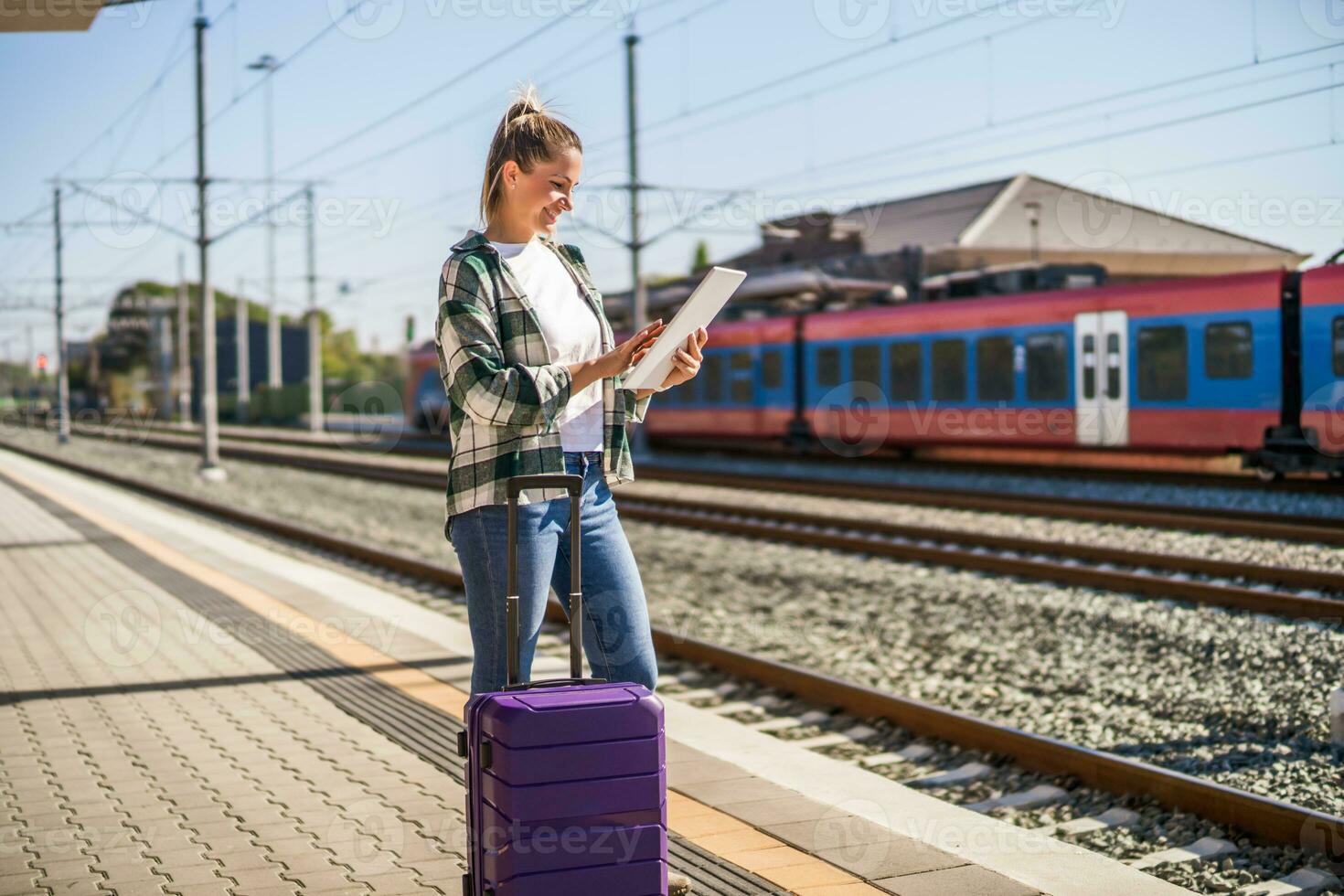 contento donna utilizzando digitale tavoletta su un' treno stazione foto
