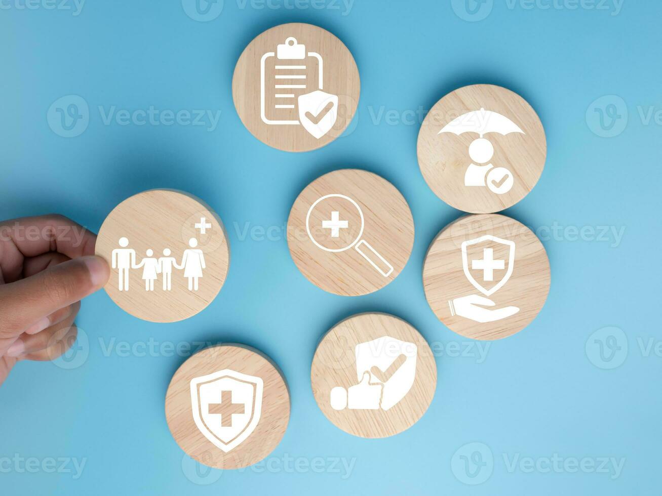 Salute e medico concetto, umano mano detiene un' legna cerchio con icone di Salute e accesso per trattamento e medicina e forniture su un' blu sfondo. foto