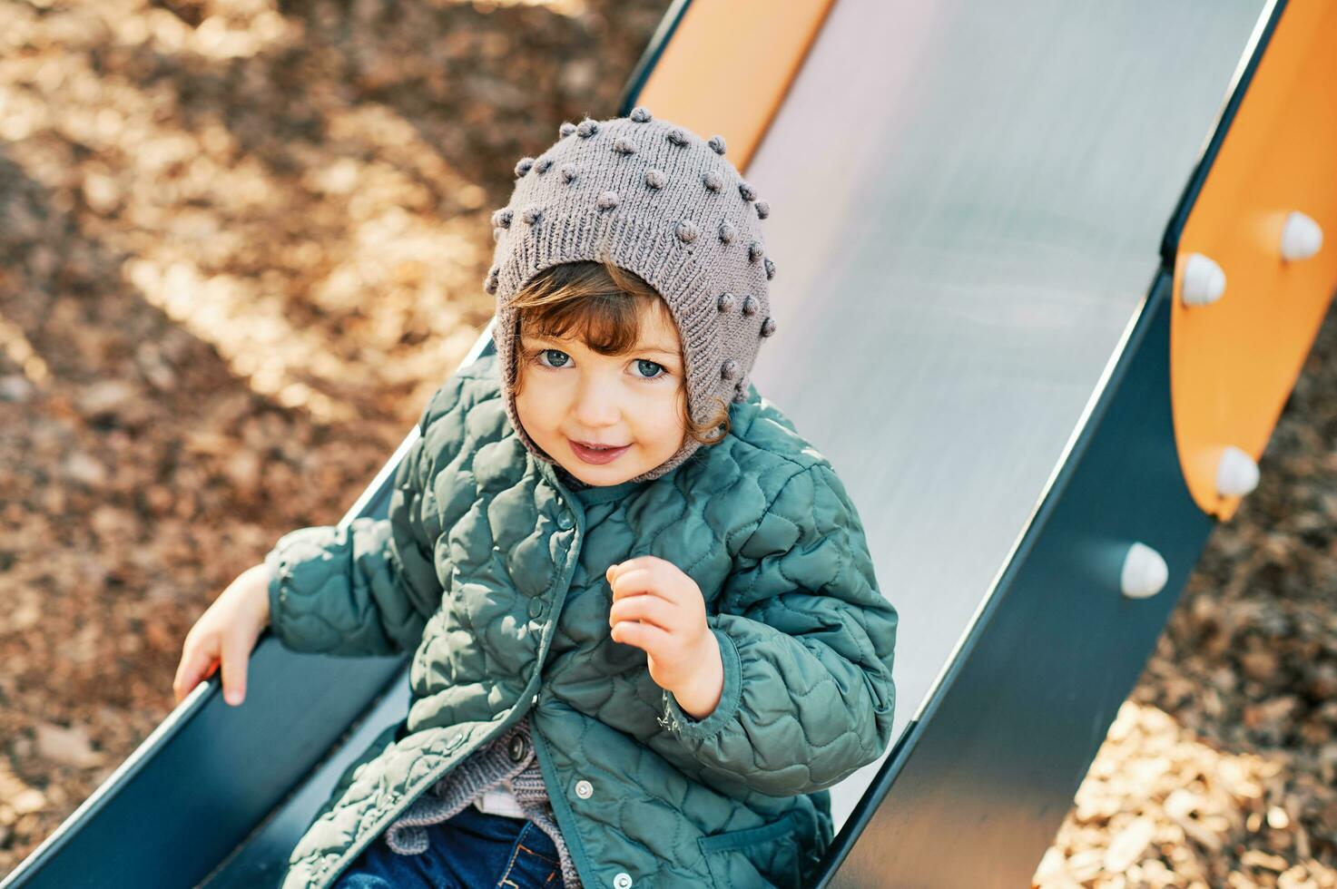 adorabile bambino piccolo ragazza avendo divertimento su terreno di gioco indossare caldo giacca foto