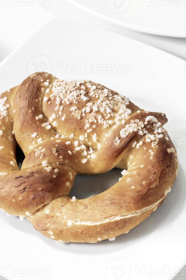 Pane pretzel tedesco biologico senza latticini vegano sul tavolo bianco foto