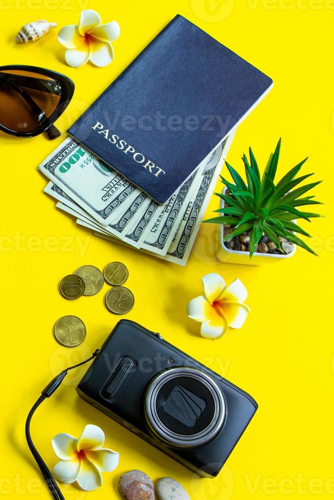 concetto di viaggio estivo. passaporto, denaro, occhiali da sole e una macchina fotografica su sfondo giallo. formato verticale foto