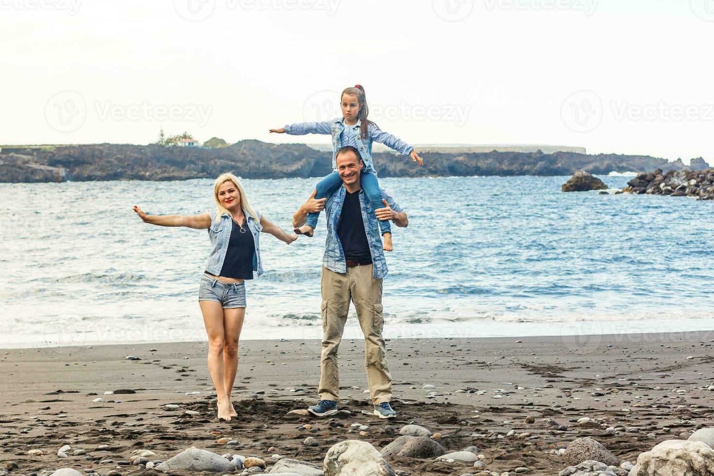 contento famiglia in piedi su il spiaggia su il alba tempo foto