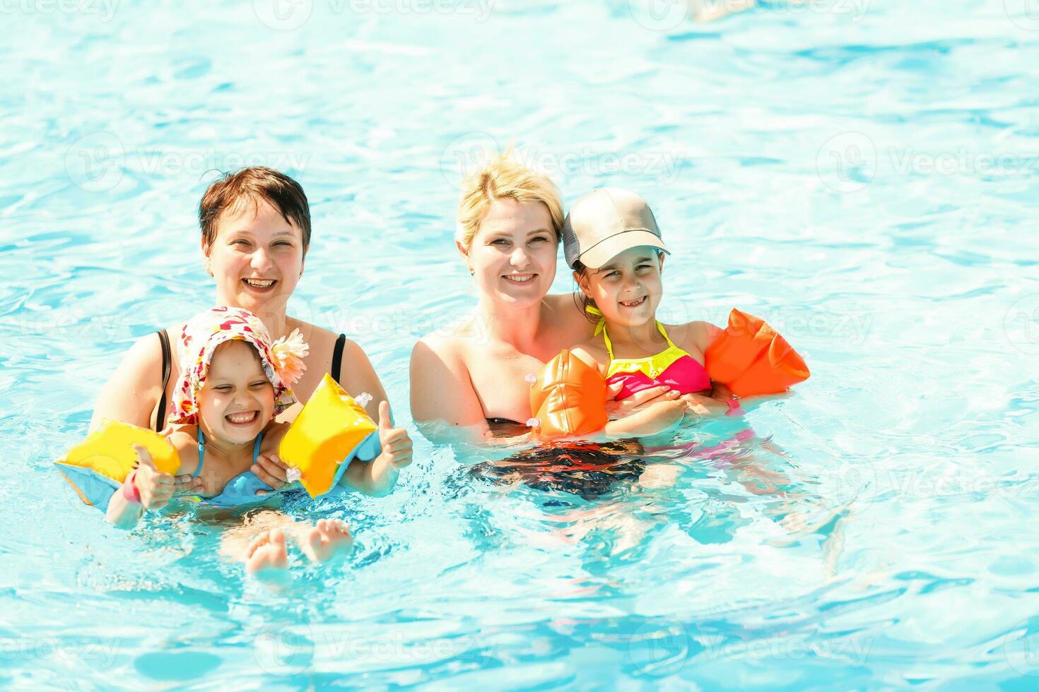 Due donne e loro bambini nel il piscina foto