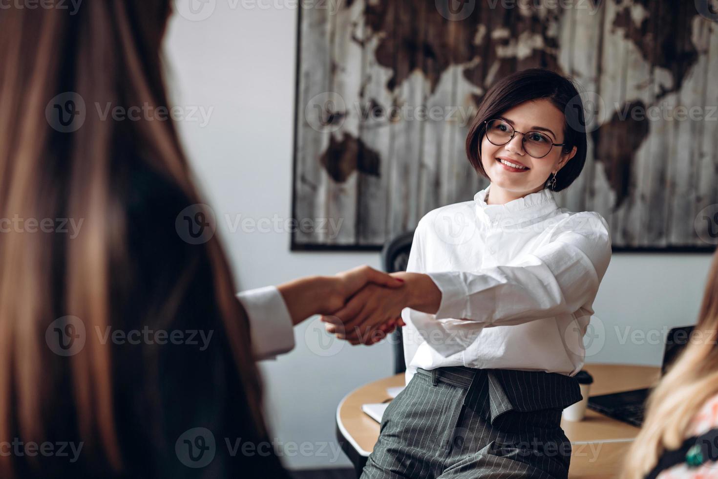 bruna fiduciosa con gli occhiali stringe la mano al suo partner. foto