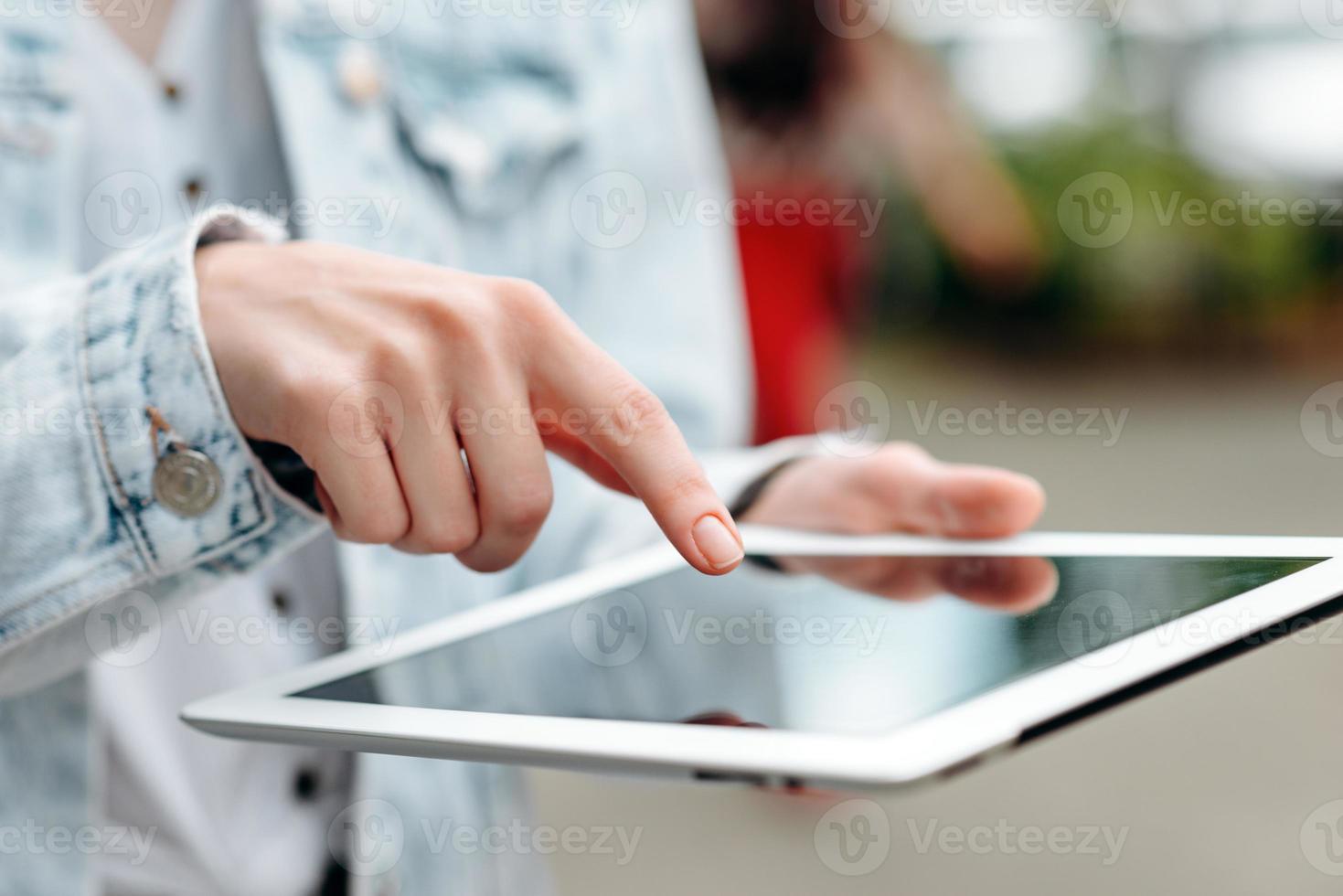 mano femminile del primo piano con un ipad. dito indice che punta allo schermo.- immagine foto