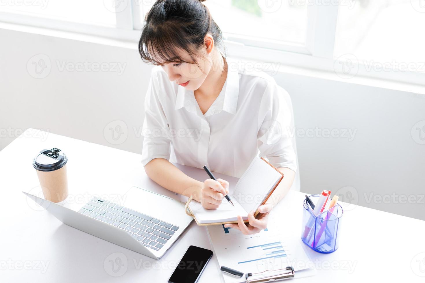 ritratto di giovane donna d'affari seduta e fare piani in un taccuino foto