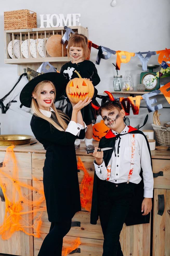 madre e bambini in cucina in piedi in costume e guardando la telecamera - concetto di halloween foto