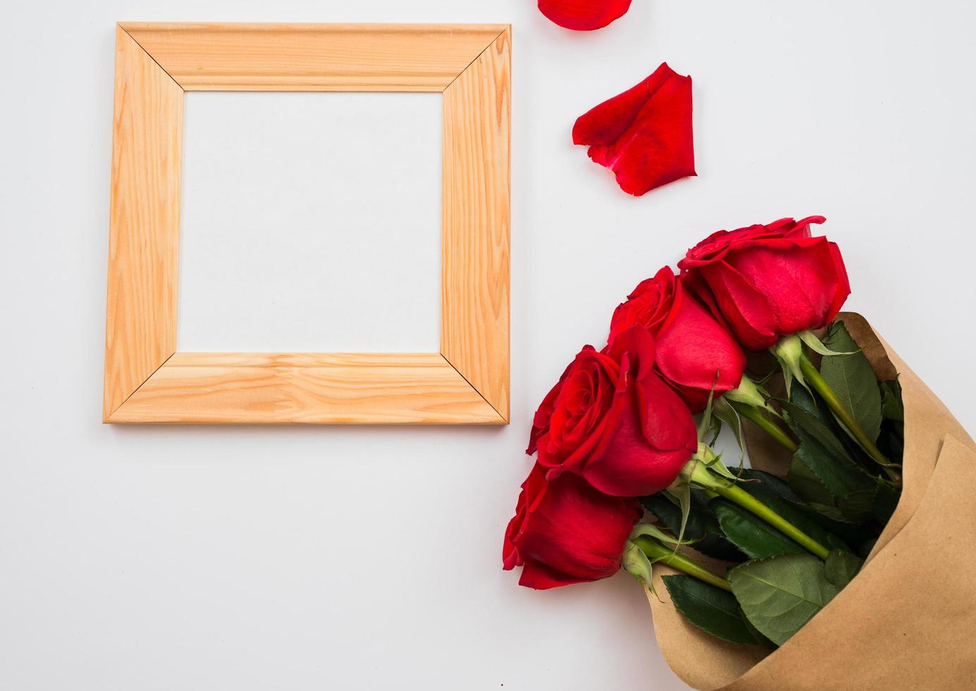 su uno sfondo bianco ci sono delle bellissime rose rosse e una cornice. posto per il testo, copia spazio foto