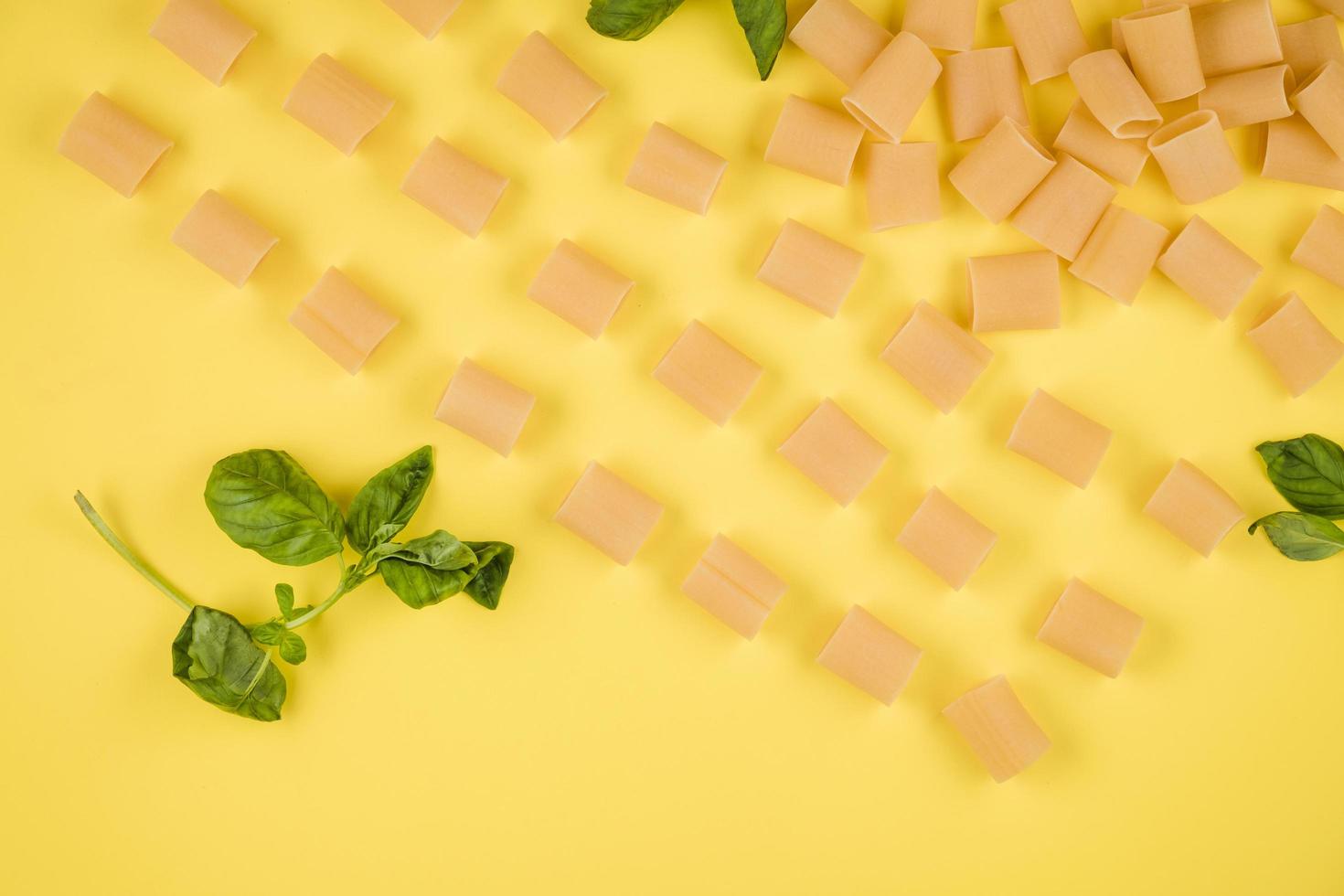 lo sfondo giallo mostra pasta italiana, basilico. concetto di cucina italiana. foto