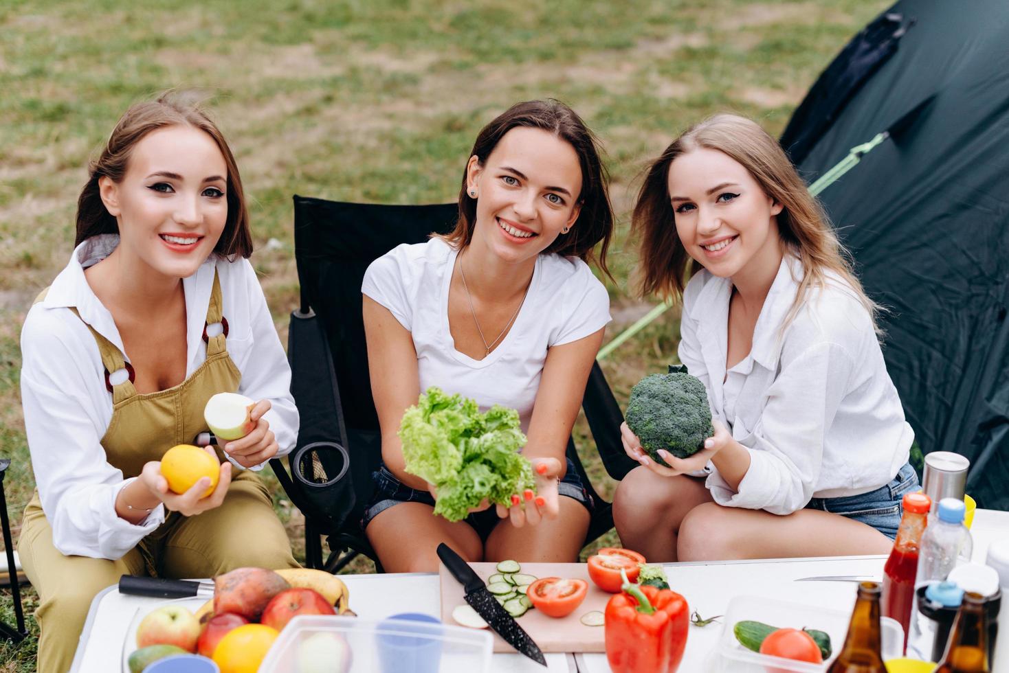 belle donne sedute al tavolo, con in mano una verdura e sorridenti allegramente foto