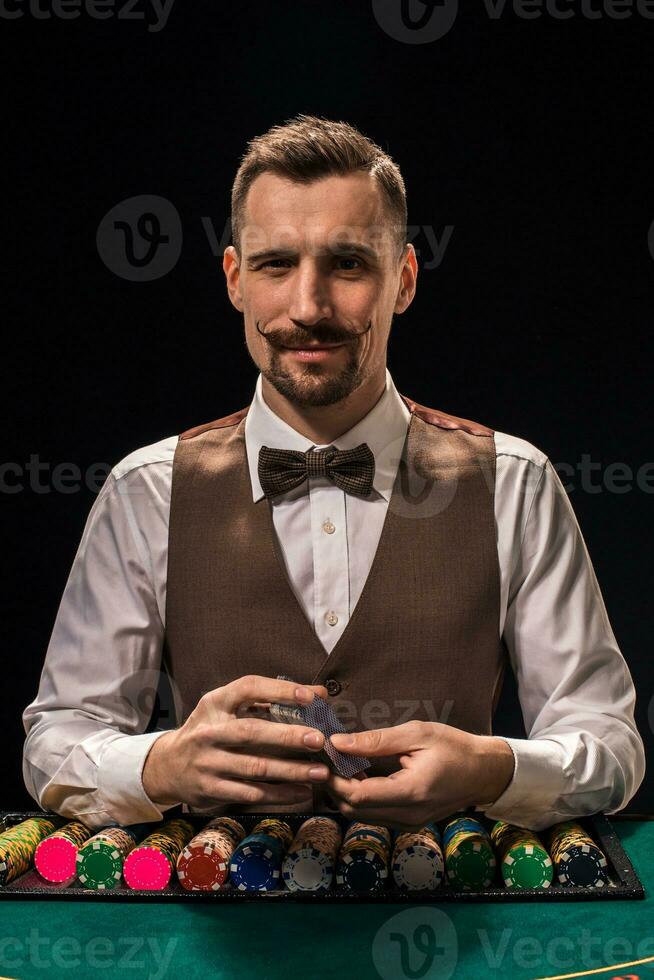 ritratto di un' croupier è Tenere giocando carte, gioco d'azzardo patatine fritte su tavolo. nero sfondo foto