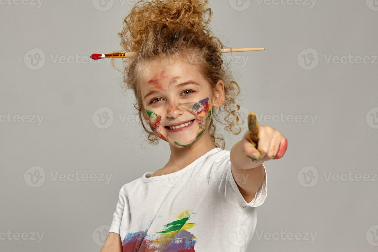 bellissimo poco ragazza con un' dipinto dita è in posa su un' grigio sfondo. foto