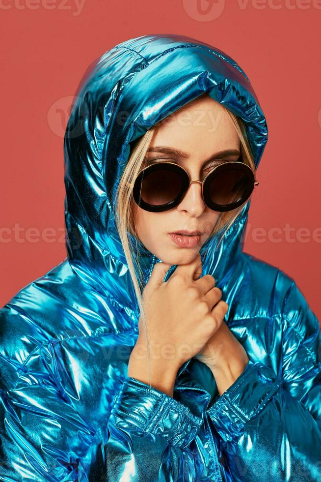 bionda sottile ragazza nel blu giù giacca coperture sua viso a partire dal vento con cappuccio foto