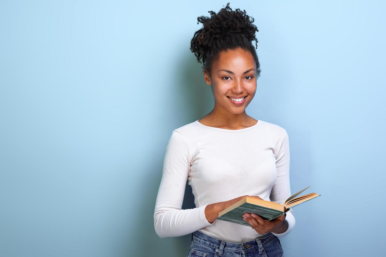 studentessa mulatta che tiene il libro in mano e studia. di nuovo a scuola . - Immagine foto