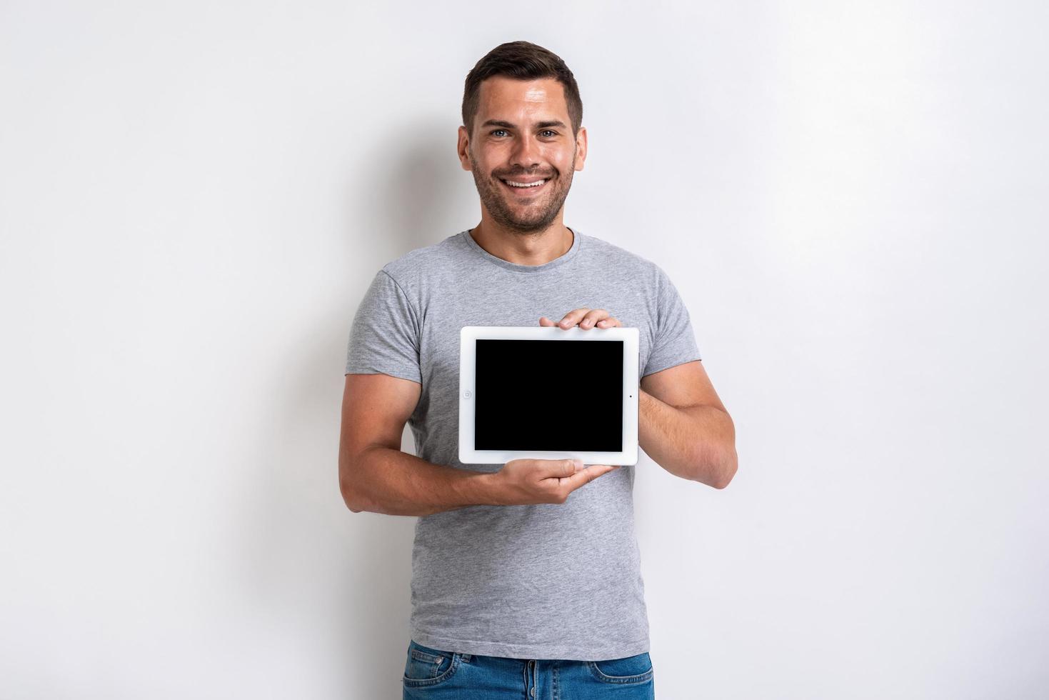 colpo dello studio dell'uomo felice che tiene un ipad con lo schermo in bianco vuoto nero. - Immagine foto