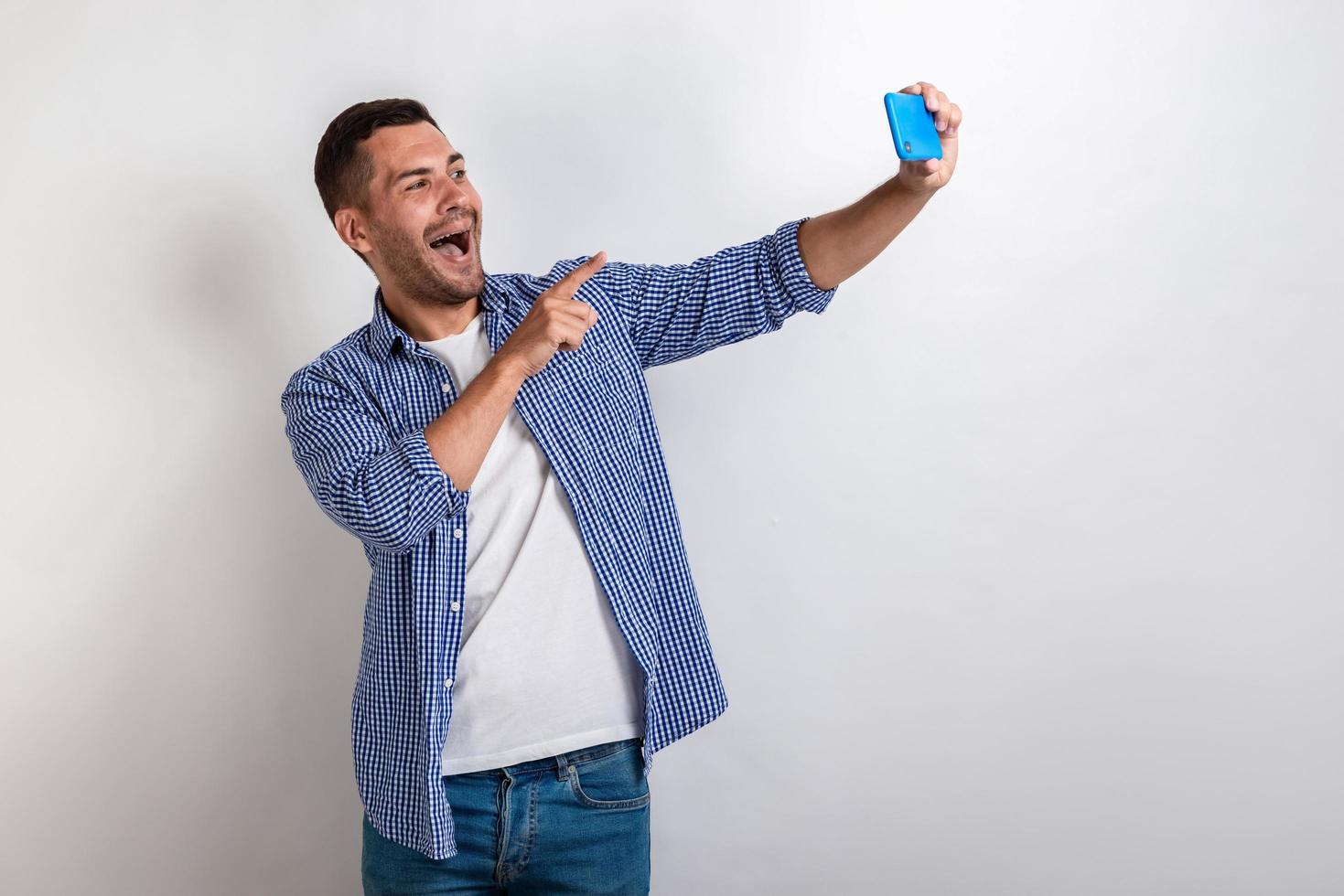 uomo felice scatta una foto selfie e indica lo schermo del cellulare.- immagine