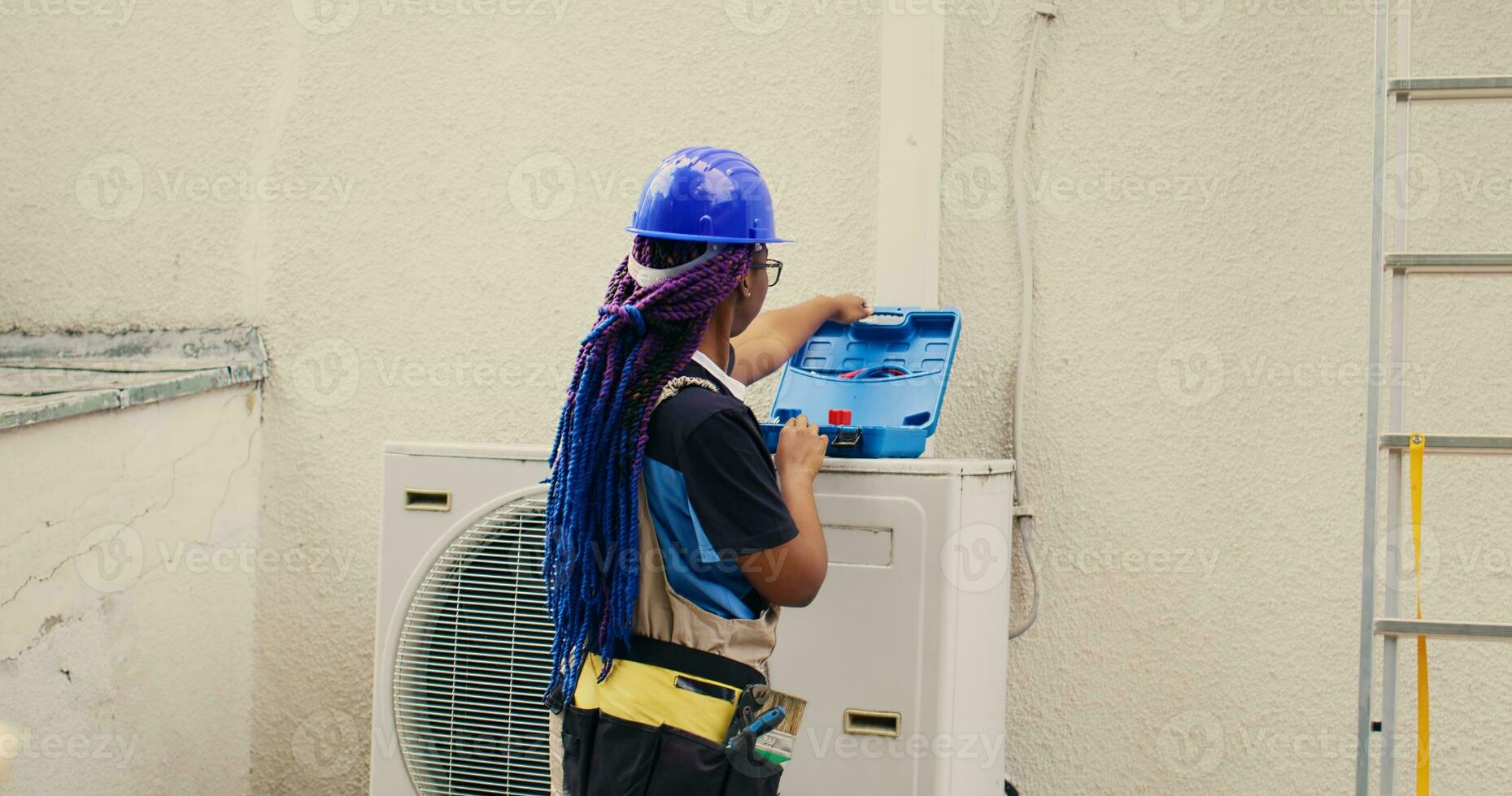 qualificato africano americano riparatore di partenza routine Manutenzione su esterno HVAC sistema, preparazione cassetta degli attrezzi. ingegnere ottenere utensili pronto per controllo difettoso aria condizionatore interno parti foto