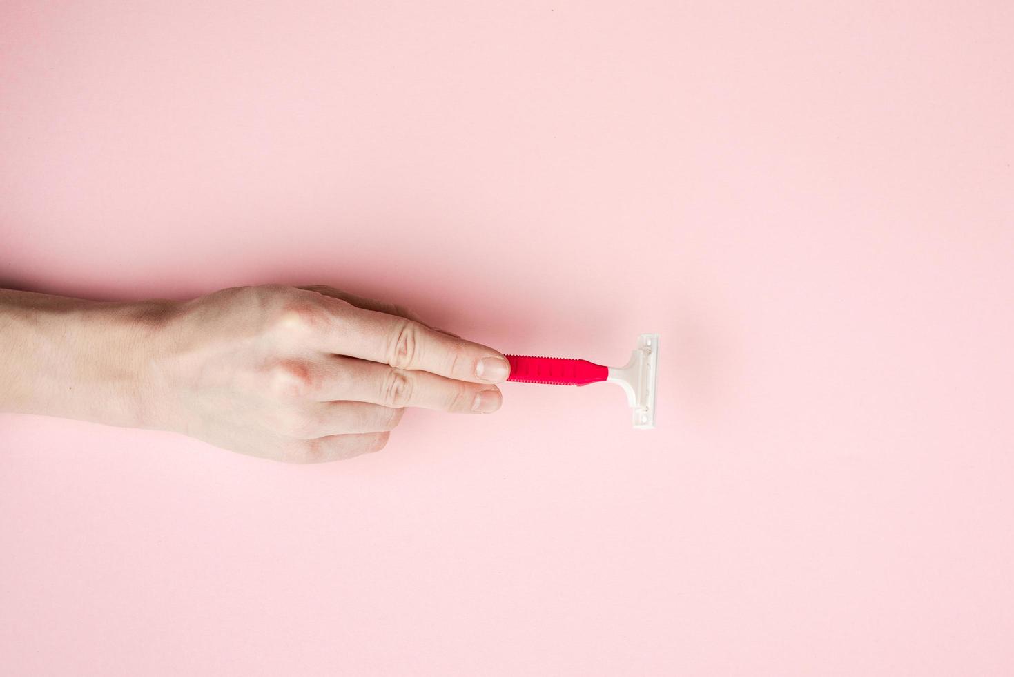 donna mano che tiene lamette da barba. isolato su sfondo rosa foto