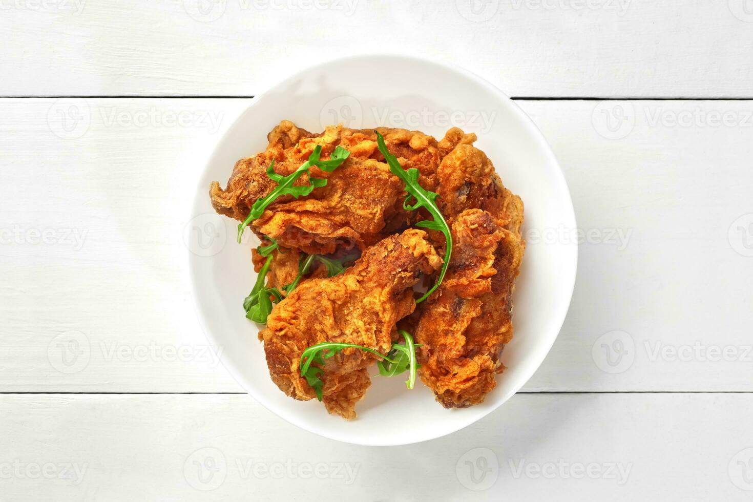 croccante fritta pollo Ali con fresco rucola nel ciotola su bianca di legno tavolo foto