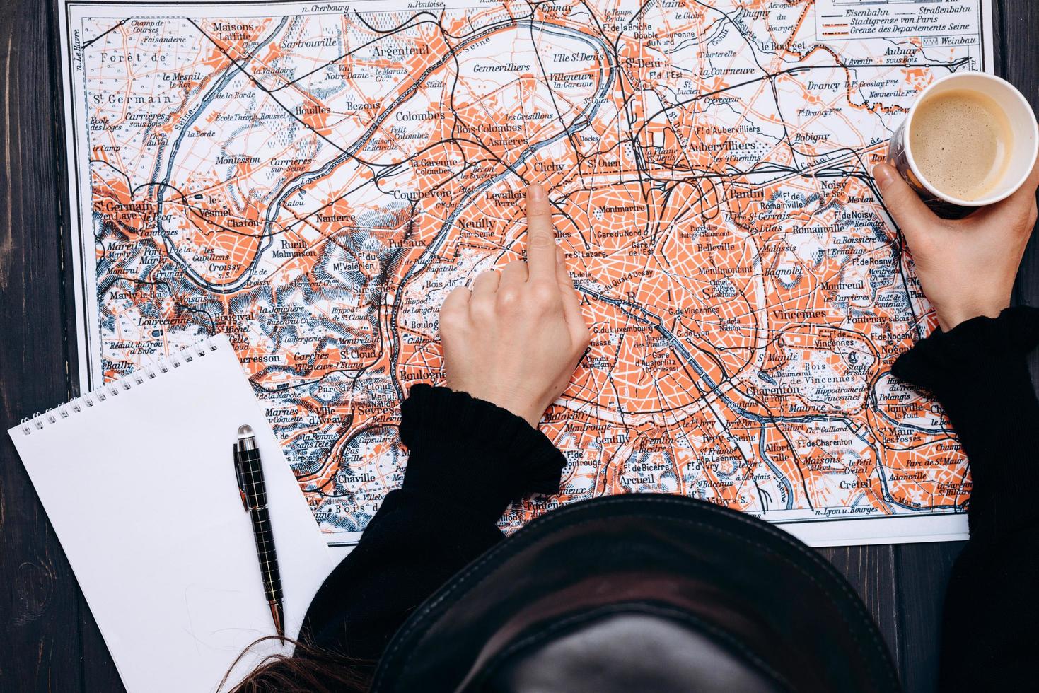 vista dall'alto di una fanciulla che indica una mappa con un caffè in mano. concetto di pianificazione del viaggio foto