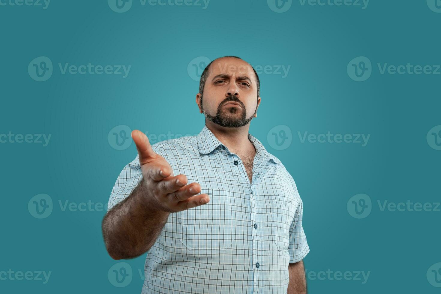 avvicinamento ritratto di un' brunet di mezza età uomo con barba, vestito nel un' leggero scacchi camicia e in posa contro un' blu sfondo. foto