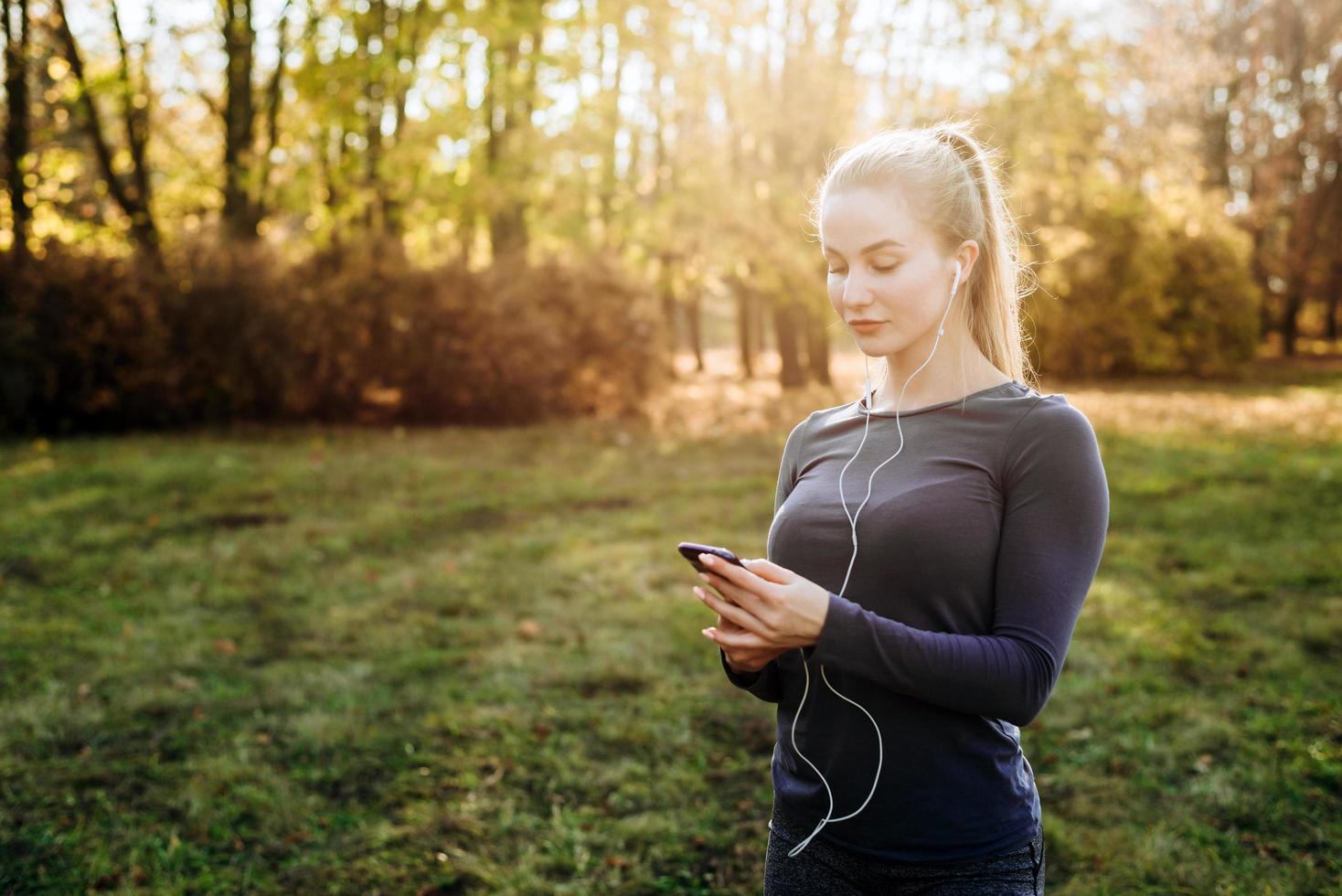 fitness nel park.girl tiene in mano lo smartphone e le cuffie. foto