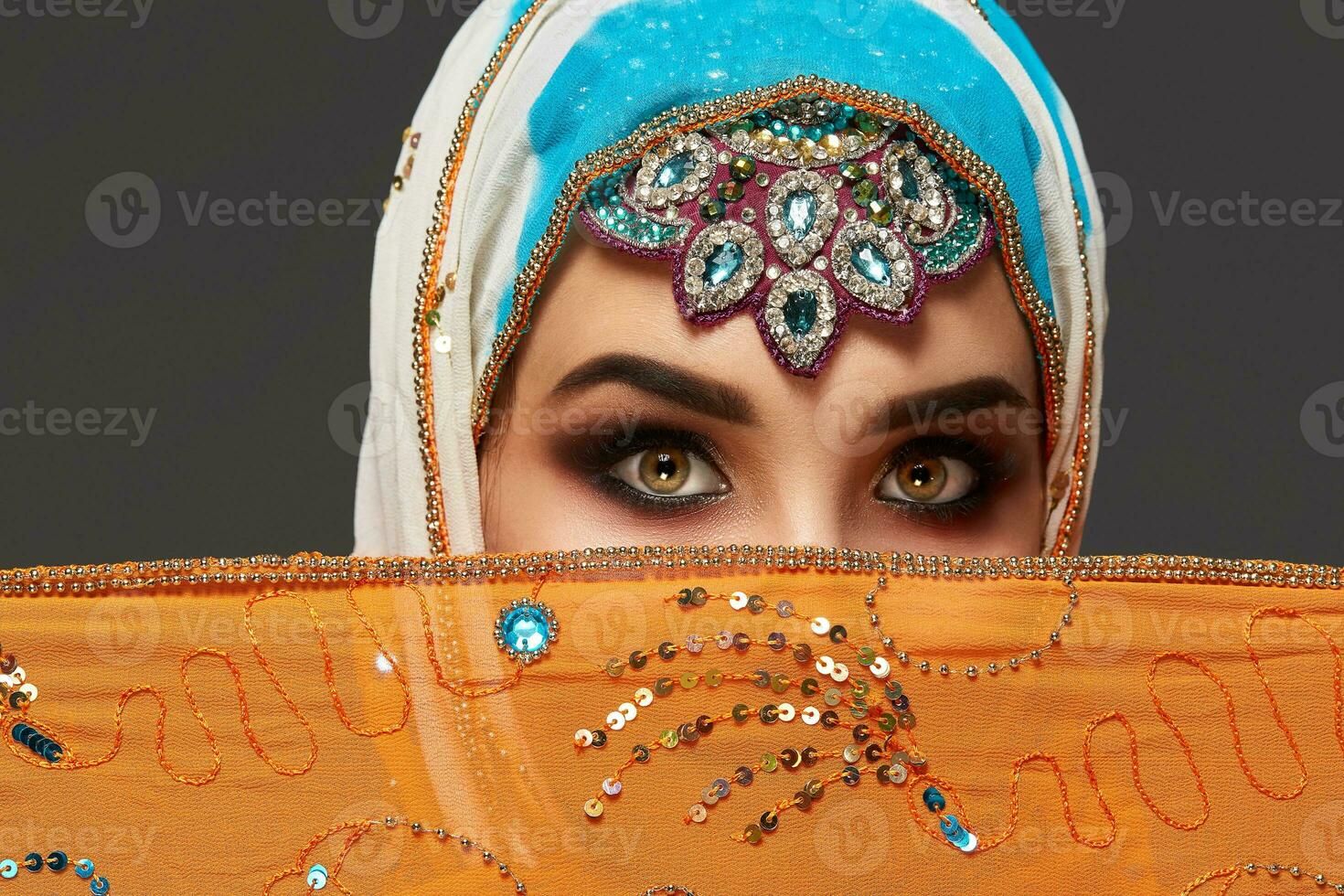 studio tiro di un' affascinante femmina indossare il colorato hijab decorato con paillettes e gioielleria. Arabo stile. foto