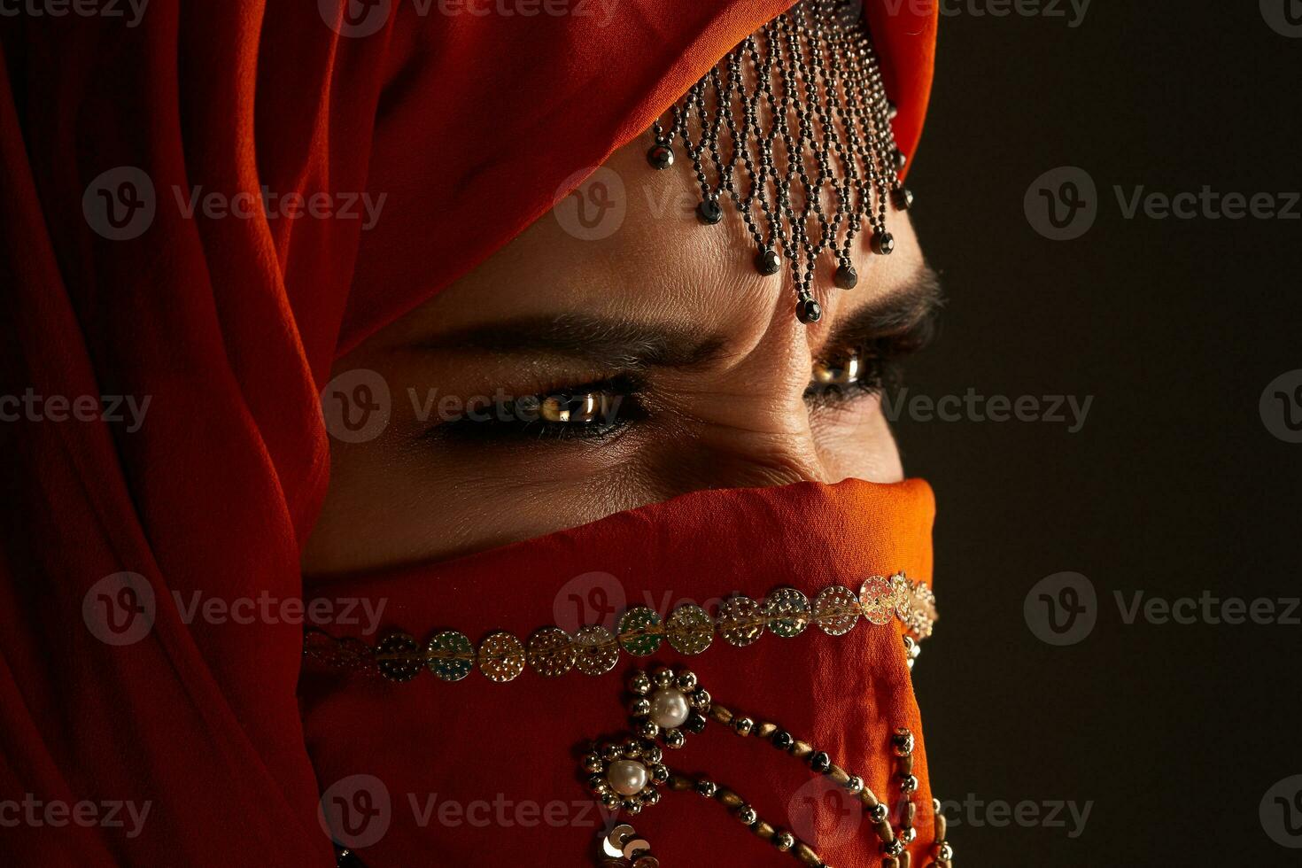 studio tiro di un' giovane affascinante donna indossare il terracotta hijab decorato con paillettes e gioielleria. Arabo stile. foto