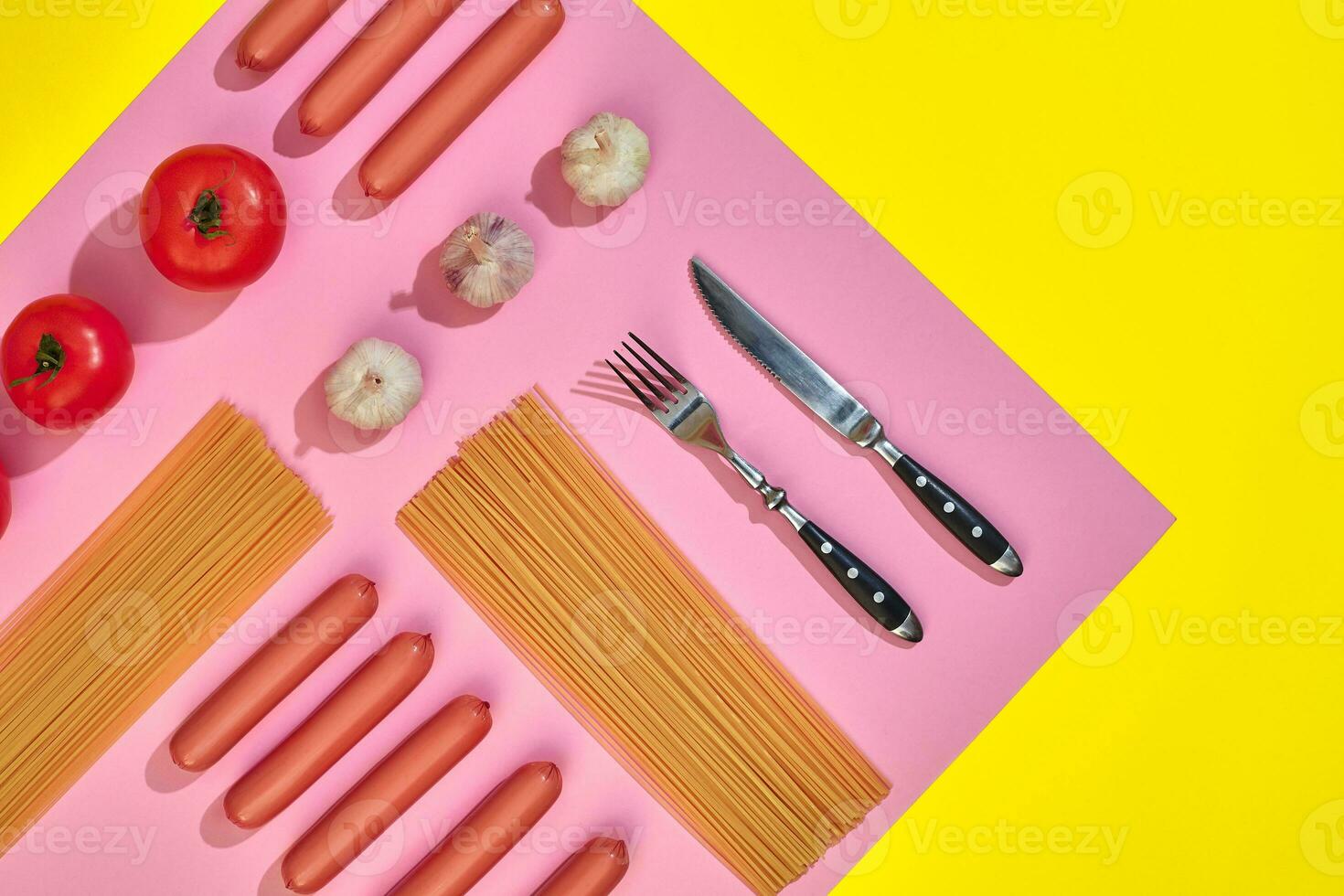 salsicce con pomodori, spaghetti e aglio su un' giallo e rosa minimo sfondo. piatto posizione. superiore Visualizza. foto