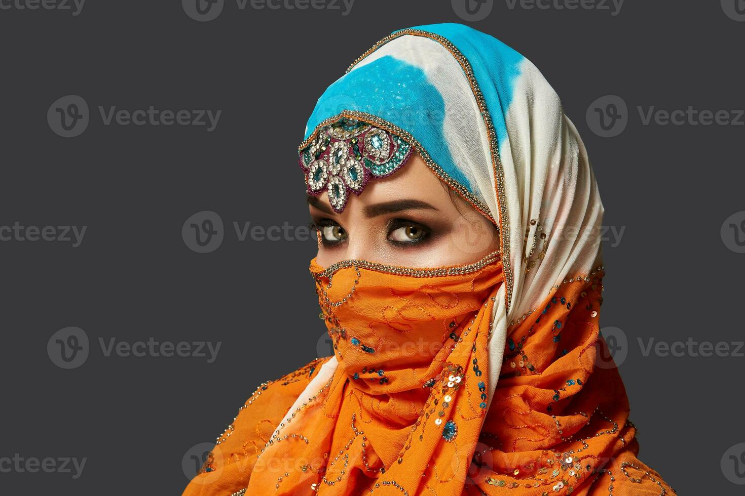 studio tiro di un' affascinante femmina indossare il colorato hijab decorato con paillettes e gioielleria. Arabo stile. foto