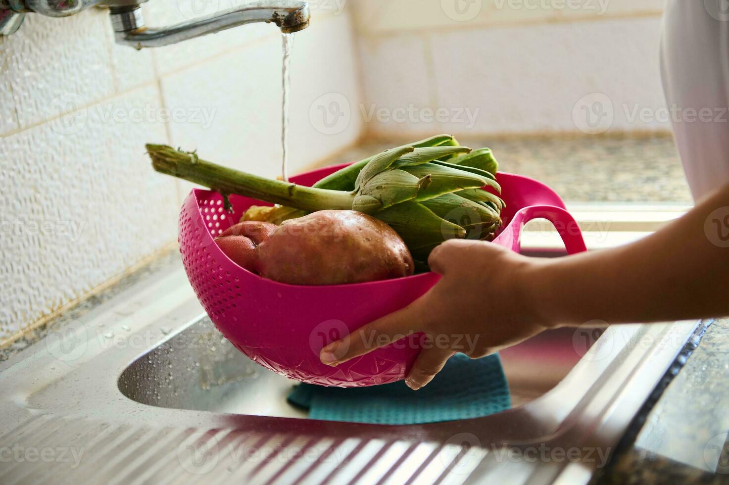 avvicinamento donna casalinga lavaggio fresco verdure sotto in esecuzione acqua, in piedi di inossidabile Lavello nel il cucina a casa foto