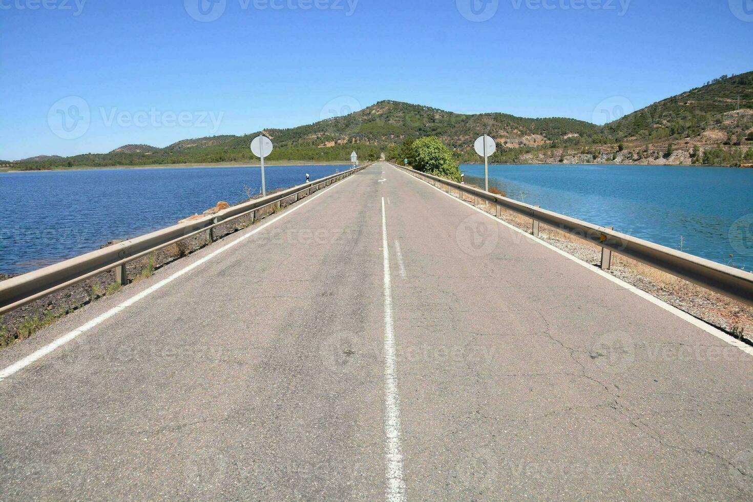 un' lungo vuoto strada con un' ponte al di sopra di un' lago foto